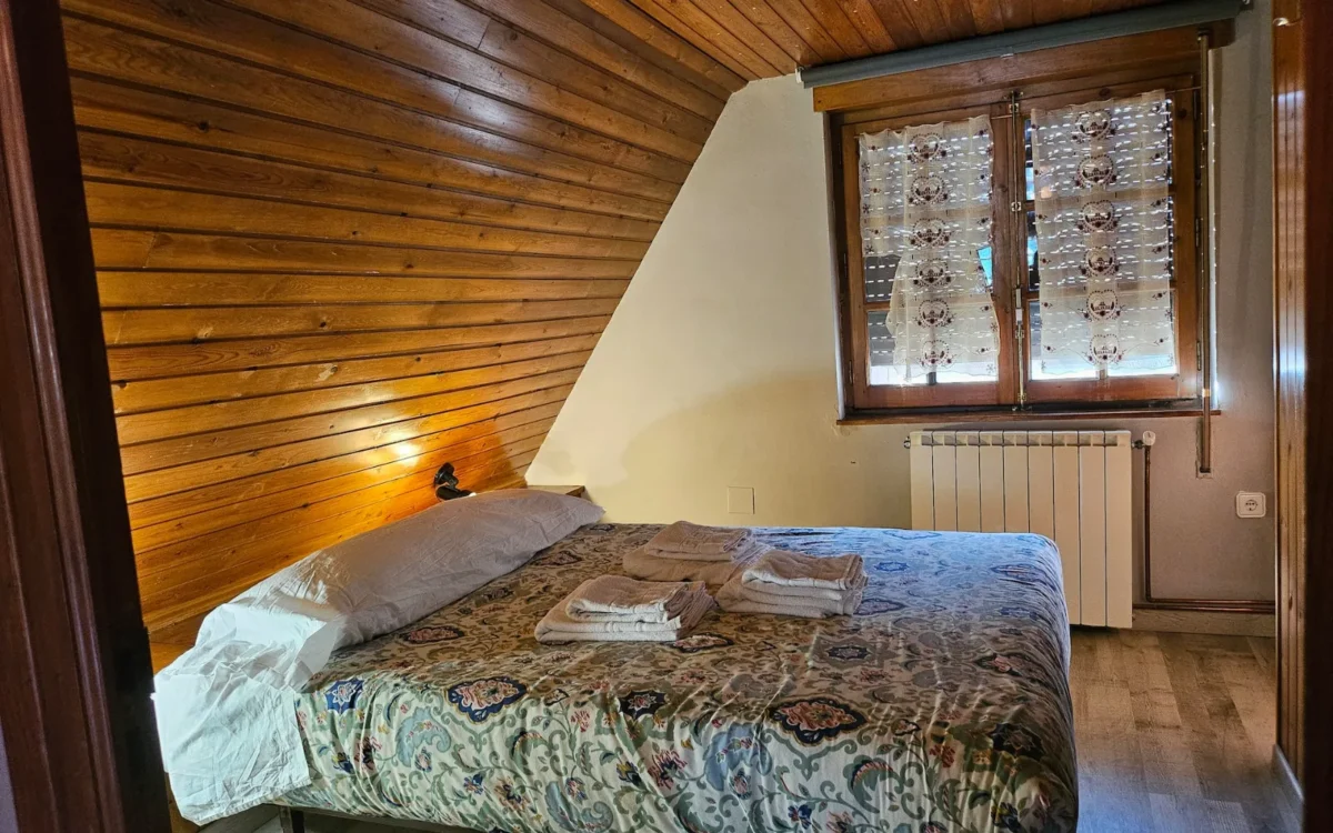 Dormitorio del apartamento con cama de matrimonio bajo el techo de madera