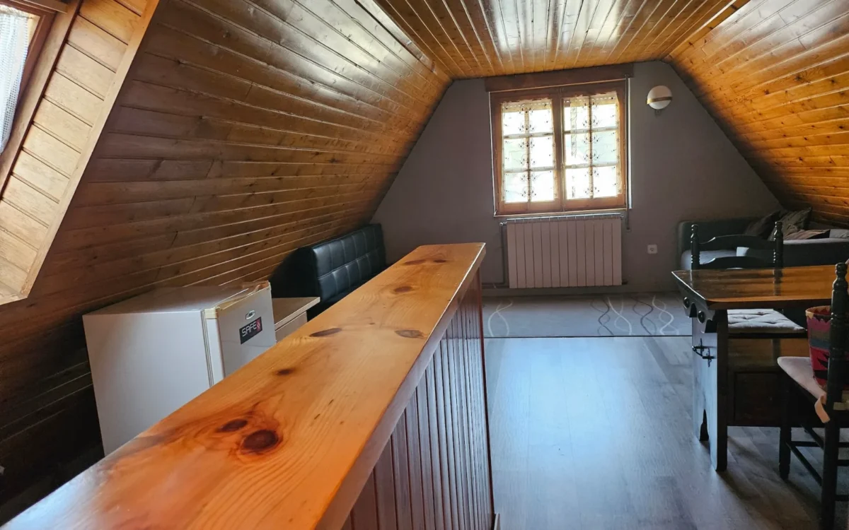 Cocina y salón del apartamento abuhardillado de Hostería Dedieu, con techo de madera