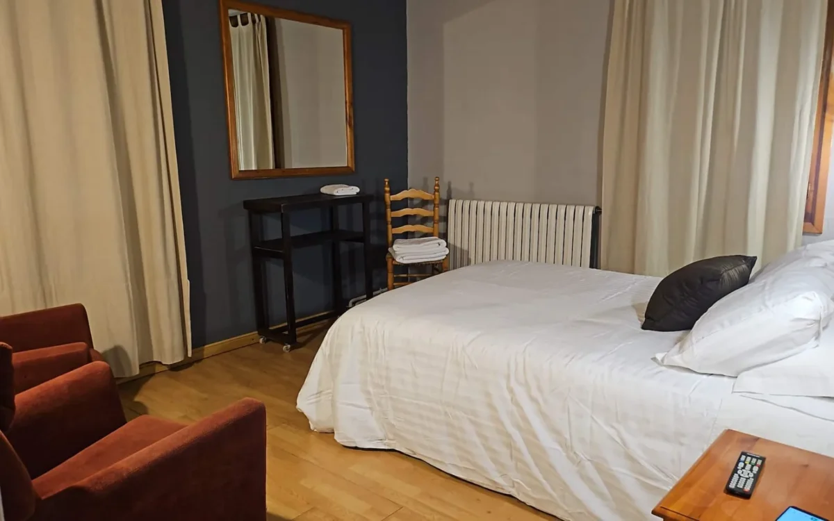 Habitación doble de Hostería Dedieu con cama de matrimonio y dos butacas rojas