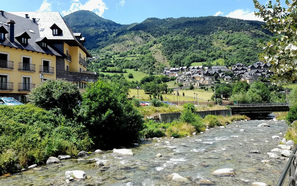 El río Garona a su paso por Vielha, con casas y montañas al fondo