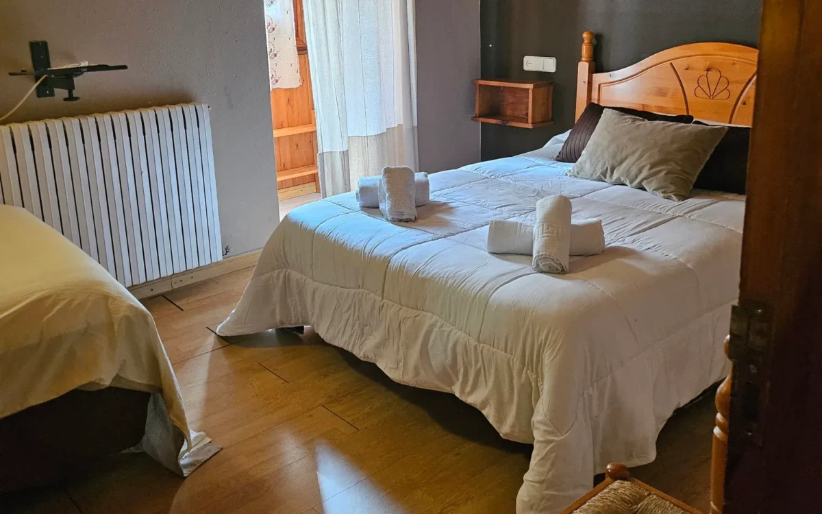 Habitación triple de Hostería Dedieu con suelo de madera y la cama individual junto a la de matrimonio